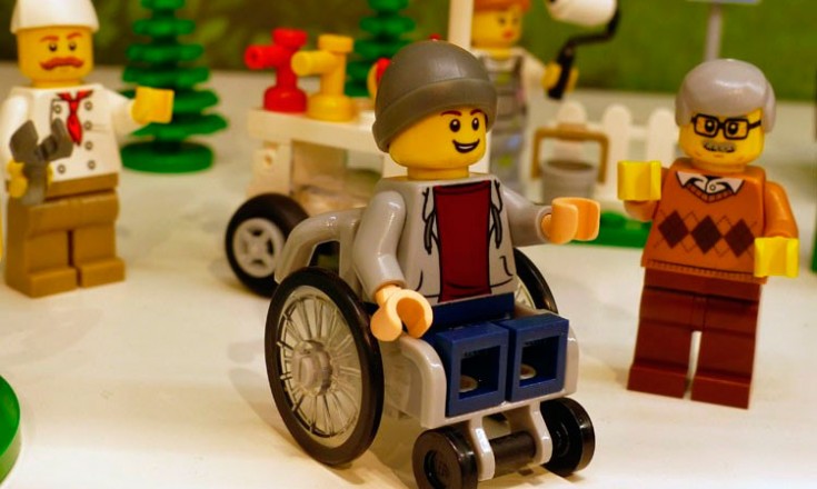 Quatro bonequinhos da Lego, um deles em cadeira de rodas