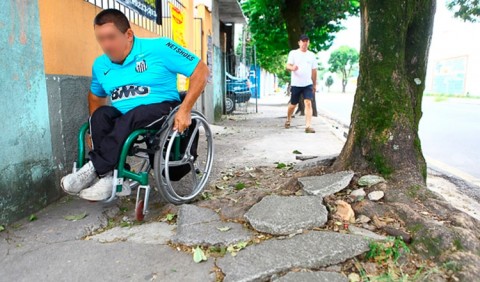 Cadeirante tentando passar em uma calçada quebrada