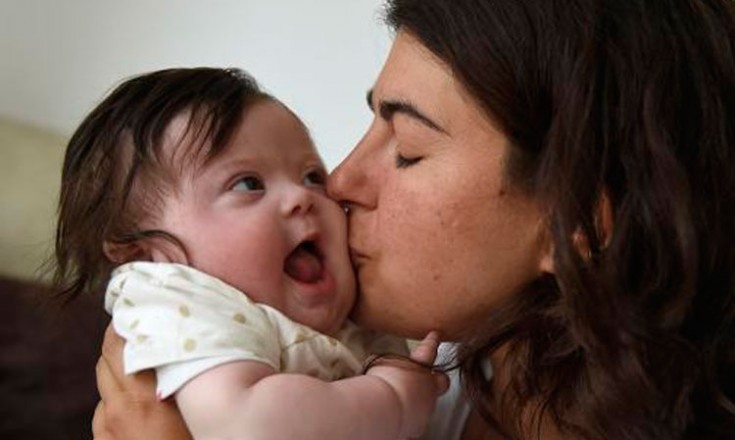 Mulher beija a bochecha de um bebê